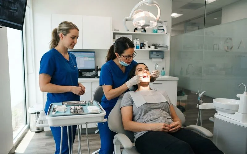 A patient and dentist looking at a chairside monitor during a routine checkup in a clean, modern clinic